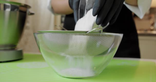 Kvinna siktar mjöl genom såll för bakning blanda ingredienser i metall skål, närbild Slow motion — Stockvideo