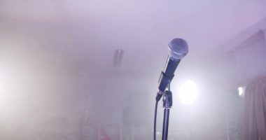 Karanlıkta sahnede konser mikrofonu ve dumanlı arka planda I ışıkları..