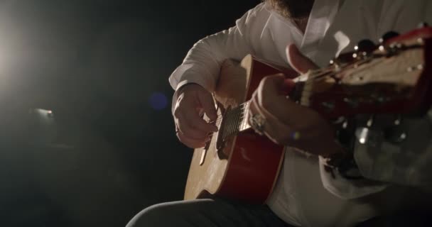 Les mains masculines jouent de la guitare acoustique dans les rayons de lumière. Gros plan. — Video
