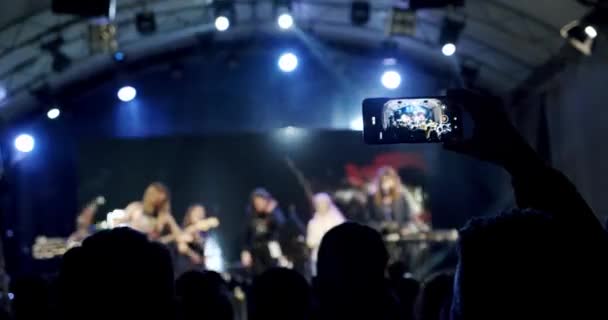 Блакитна силует людей тримає руки з телефоном в руці і знімає відео на концерті. Повільний рух — стокове відео
