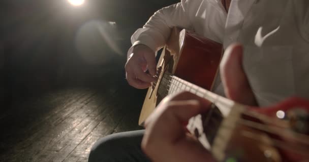 男性の手は光の光線でアコースティックギターを演奏します。接近中だ。V2 — ストック動画