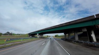 Bulutlu bir havada kavşak köprüsünün altında otoyolda araba sürüyorum. Ön yolcu koltuğundan POV görüntüsü. - Evet. Yüksek kalite 4k görüntü