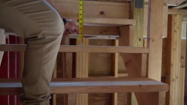  İnşaat işçisi, Ev Yenileme, Tamir ve İnşaat 'taki ahşap merdiven büyüklüğünde şeritlerle ölçüm yapıyor. Yüksek kalite 4k görüntü