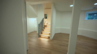 Yenilenmiş bir evin içinde, ahşap ışıklı merdivenleri ve metal parmaklıkları olan modern bir merdiven. Temiz çağdaş tasarımla aydınlık bir iç mekan. Yüksek kalite 4k görüntü