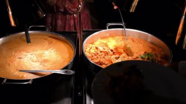  Hint mutfağı, yemek servisi, açık büfe, kültürel kutlama ziyafetleri. Kremalı köri soslu tencereler ve taze otlarla süslenmiş tereyağlı tavuk. Yüksek kalite 4k görüntü