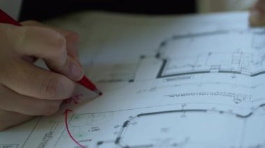 Mimari tasarım projesi, mimar tasarımcı mühendis beyin fırtınası ve binanın iç çizimi, kat planı, kağıda basılmış taslaklar üzerine kırmızı ifadeler yazmak. Yüksek kalite 4k görüntü