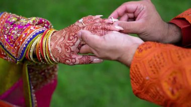 Damat geleneksel kınalı gelin elinin alyansını takıyor. Hindu parlak gelinliklerinin unsurları. - Evet. Yüksek kalite 4k görüntü