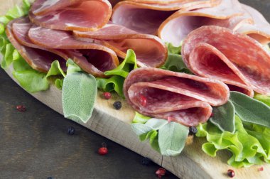 Prosciutto, pastırma, salam ve sosis ahşap zemin üzerine kurulu. Soğuk kesim
