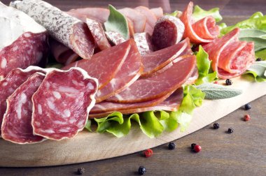 Prosciutto, pastırma, salam ve sosis ahşap zemin üzerine kurulu. Soğuk kesim