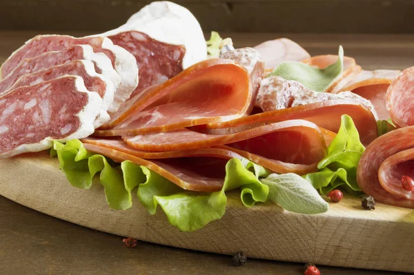 Prosciutto, pastırma, salam ve sosis ahşap zemin üzerine kurulu. Soğuk kesim