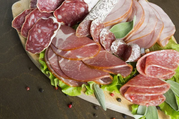 Prosciutto, pastırma, salam ve sosis ahşap zemin üzerine kurulu. Soğuk kesim