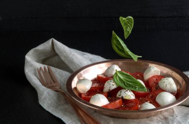 Olgun domatesli Caprese salatası ve taze fesleğen yapraklı mozzarella. İtalyan yemeği..