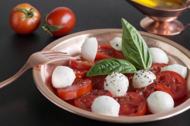 Olgun domatesli Caprese salatası ve taze fesleğen yapraklı mozzarella. İtalyan yemeği..