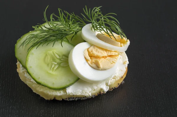 Simit yumurta ve siyah arka plan üzerine salatalık ile