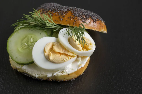 Simit yumurta ve siyah arka plan üzerine salatalık ile