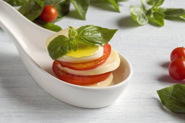 Olgun domatesli Caprese salatası ve taze fesleğen yapraklı mozzarella. İtalyan yemeği..