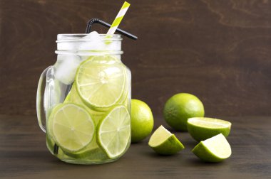 Mason kavanoza bardak limonata kireç ve saman ahşap backgr üzerinde