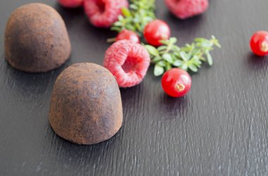 Ahududu ile siyah arka plan üzerine çikolata truffles.