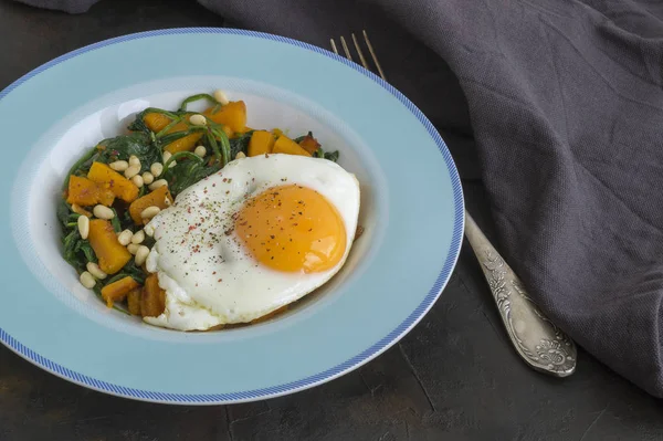 Sunny side up egg with spinach and pumpkin.