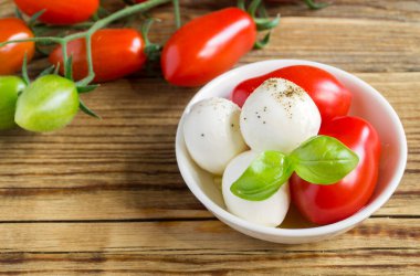 Olgun domatesli Caprese salatası ve taze fesleğen yapraklı mozzarella. İtalyan yemeği..