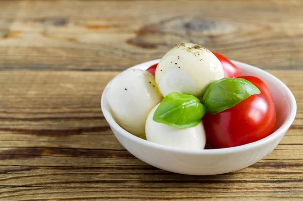 Olgun domatesli Caprese salatası ve taze fesleğen yapraklı mozzarella. İtalyan yemeği..