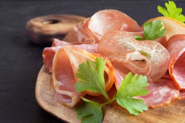 Prosciutto, pastırma, salam ve ahşap bir arka planda sosis ile ahşap kesim tahtası. et tabağı