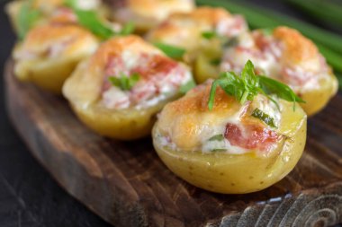 Peynirli fırında patates, pastırma, tahta üzerinde maydanoz..