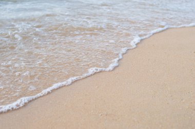 Kum plajı üzerinde kabarcıklar ile su dalgalar deniz