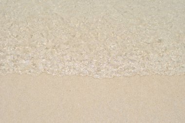 Kum plajı üzerinde kabarcıklar ile su dalgalar deniz