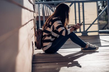 ahşap zemin üzerinde güzel kız oturma ve oyun akıllı telefon