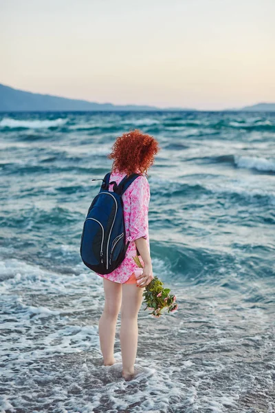 Alone young woman touching sea with feet and dreaming