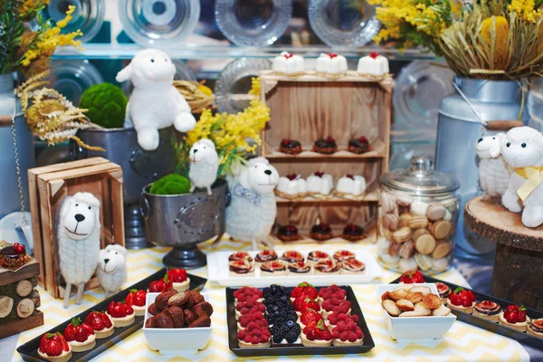 Concept candy bar with felted toy labs decorated with fresh berry cupcakes