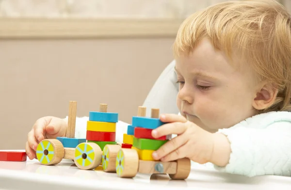 An inquisitive kid plays with educational toys while sitting at his children's table. Close up. Copy space.