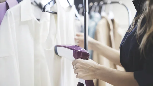 Femme utilisant de la vapeur pour repasser une chemise dans un magasin — Photo