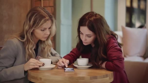 Deux jeunes amis attrayants parlent dans un café, téléphone et photos pan shot — Video