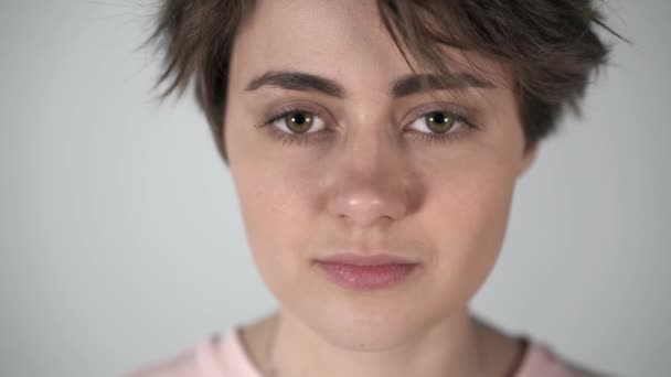 Kısa saç yanıp sönen ve yarı gülümseyen genç bir kadın portresi — Stok video
