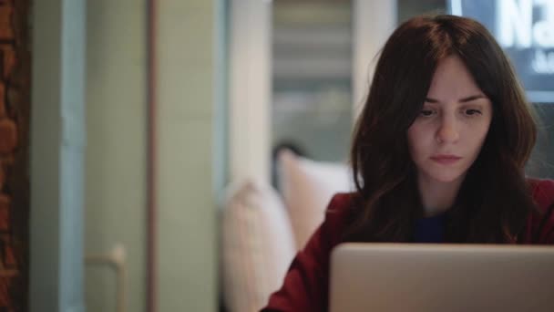 Centrerad ung kvinna med mörkt hår arbetar med en bärbar dator hemma — Stockvideo