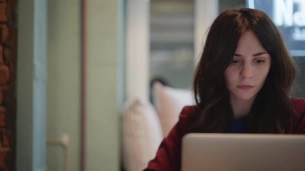 Centered young woman with dark hair working with a laptop at home — Stock Video