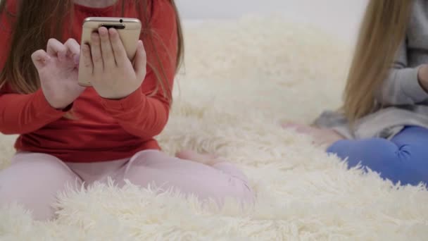 Dvě malé holčičky v pyžamu surfování na webu s smartphone na posteli — Stock video