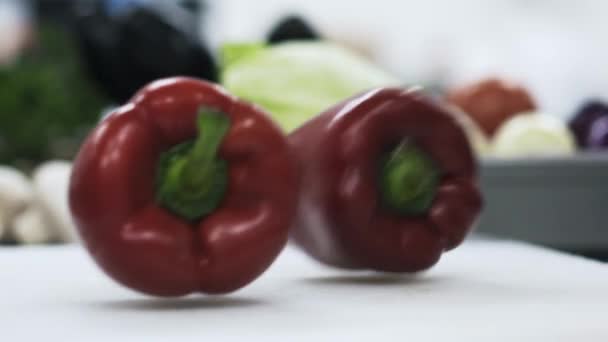 Savoureux poivrons rouges tombant sur une table blanche — Video