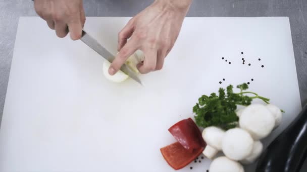 Bovenaanzicht van een chef-kok hakken de ui in een restaurant — Stockvideo