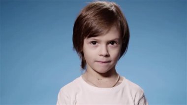 Süper ağır çekim küçük şirin bir çocuk kameraya, mavi arka planı arıyorum