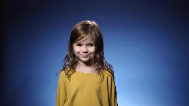 Linda niña riendo confeti cayendo, galleta, fondo azul cámara lenta — Vídeos de Stock