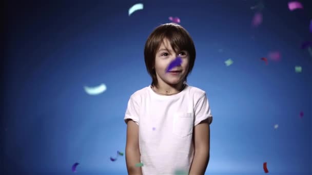 Câmera lenta do menino bonito surpreendido por bolacha e sorrindo, fundo azul — Vídeo de Stock