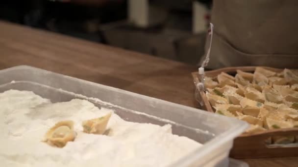 Mann bestreut Tortellini mit Blumen und legt sie in eine Holzkiste — Stockvideo