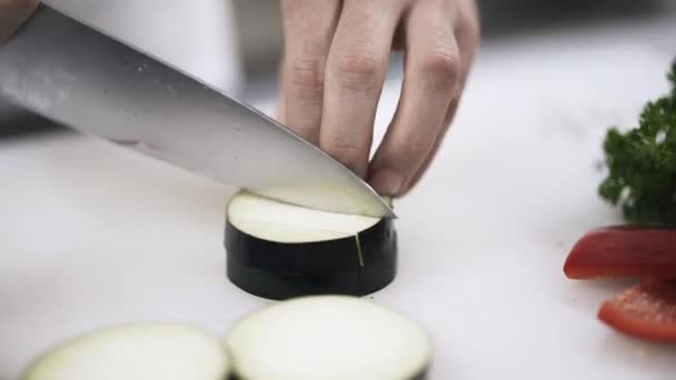 Manos de un chef haciendo cubos de berenjena — Vídeo de stock