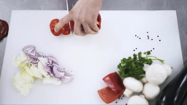 Blick von oben auf den gelernten Koch, der rote Paprika schneidet — Stockvideo