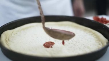 Bir kepçe ile bir Pizza Chef dökülen domates sosu