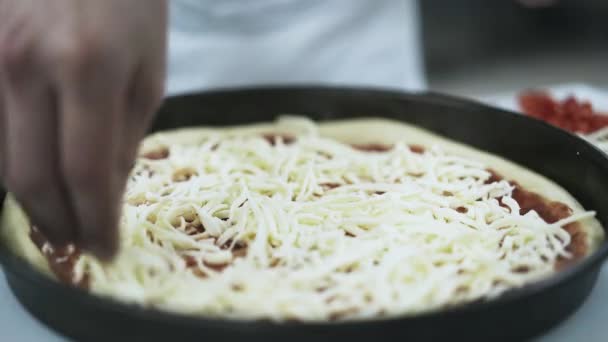 Chef covering pizza with cheese in a pizzeria kitchen — Stock Video