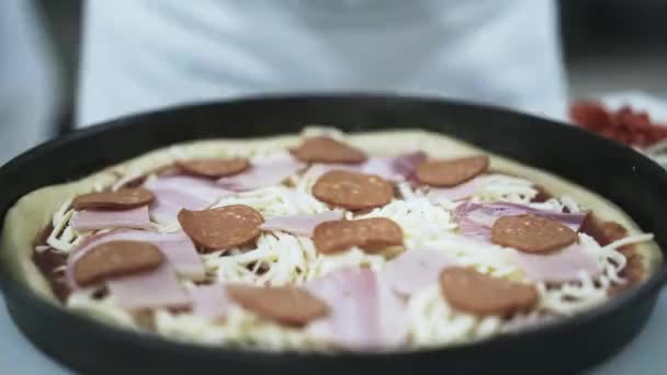 Chef colocando fatias de tomate em pizza em uma cozinha pizzaria — Vídeo de Stock